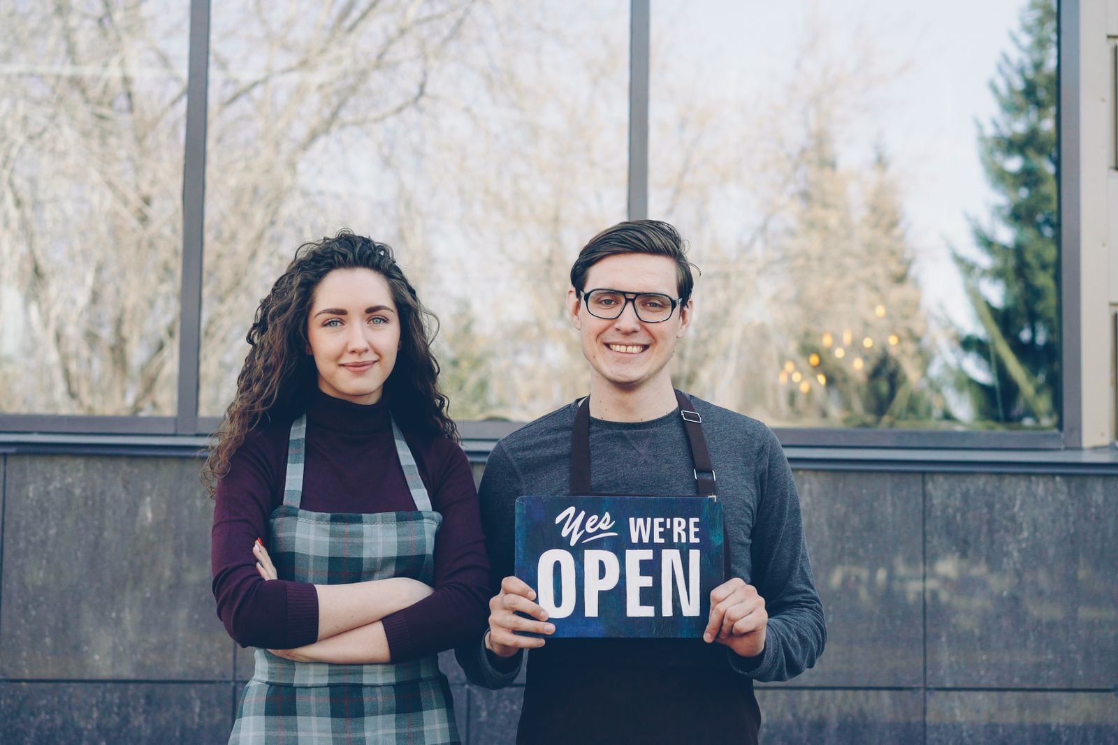 Two business owners holding an open sign at the launch of their new business